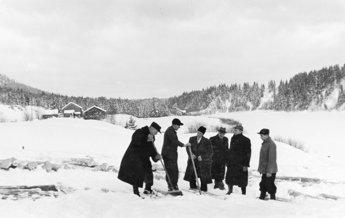 Forsøk med fargemerking av fløtingstømmer på ei snødekt isflate i nærheten av Rena i Åmot i Østerdalen i 1937. Tømmeret var lagt i såkalte flakvelter. «Flakene» besto av tømmerstokker som var lagt forholdsvis tett og parallelt, vinkelrett på en eller to underlagsstokker. Når tømmeret var tillagt på denne måten fikk tømmermålerne, som skulle besiktige, klassifisere og måle hver enkelt stokk, god oversikt og «klaverom». Forutsetningen for at dette skulle fungere godt var at tømmeret ble framkjørt og tillagt i flakvelter seint på vinteren, slik at det ikke ble nedsnødd før tømmermålerne kom. I så fall møtte snøen måkes eller kostes bort. Dette var antakelig spesielt viktig her, for det var sannsynligvis umulig å få malinga til å feste seg på snøete, isete eller våte stokker. Noen av mennene som var til stede var antakelig tømmermålere, andre var muligens ledere eller tillitsvalgte fra Glommen Tømmermåkling eller Glomma fellesfløtingsforening- Fargemerking av fløtingsvirke ble ikke vanlig i norske vassdrag før i 1960-åra.