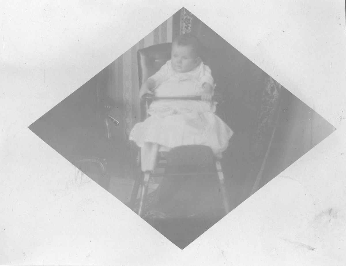 Spedbarn sitter i stol i 1912. Antagelig Niels Frederik Aall
