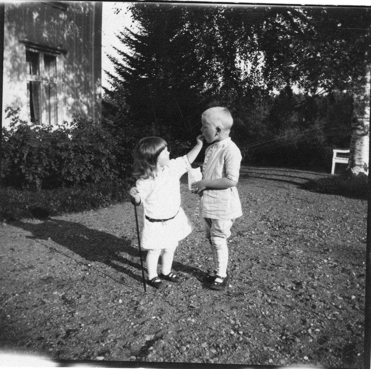 Foto av søsknene Nils Fredrik og Cecilie Aall utenfor hus i Dal, 1919. Cecilie mater sin bror