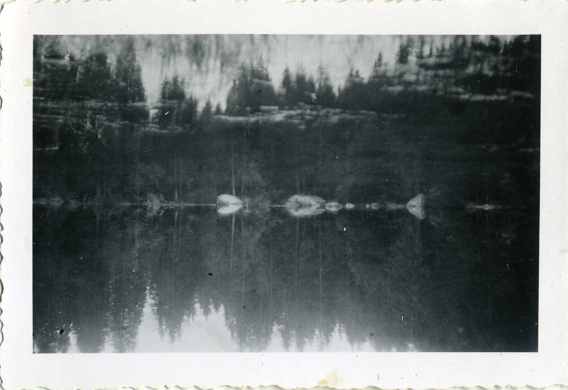 En sjö där skogen i bakgrunden speglas.