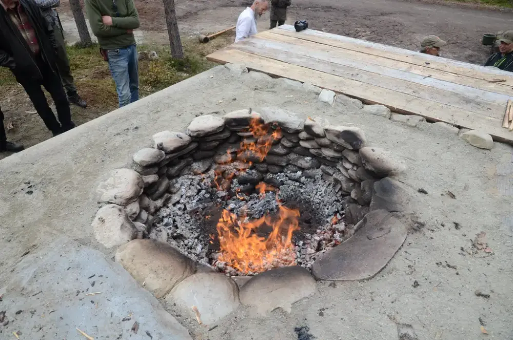 Bildet viser folk som står rundt ei grop med flammer.