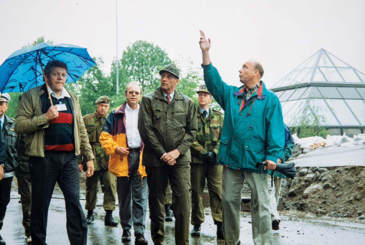 Kong Harald på flom inspeksjon i Strandgaten i Hamar sommeren 1995. Fra venstre teknisk sjef Torleif Bjelde Jensen, rådmann Svein Skaaraas (gul jakke), Kong Harald og ordfører Odd Aspeli.