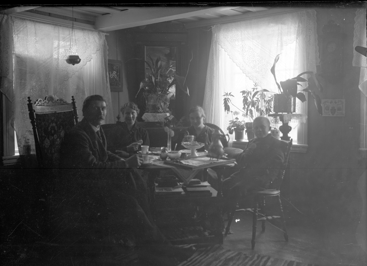 Gruppeportrett i interiør. Familie rundt stuebord 

Fotosamling etter fotograf og skogsarbeider Ole Romsdalen (f. 23.02.1893).