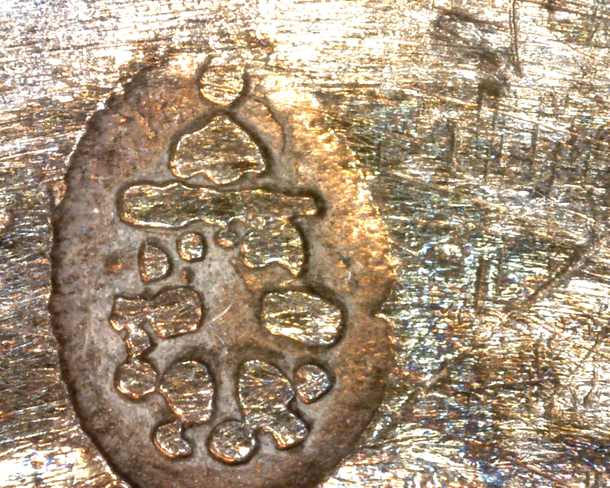 Krus av keramikk, med lokk av sølv. Kruset er farget oransje, hvorpå nederste del av korpus og håndtak er mørkere farget. Øverst og nederst på kruset er det dekorative riller. Hankfeste av sølv, med stående palmett. Lokk av sølv, med en tysk sølvdaler fra perioden 1620-1638.