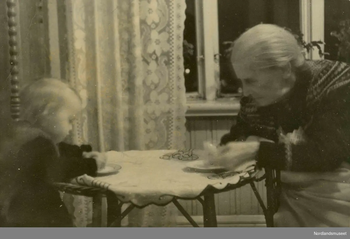 En eldre kvinne og et lite barn sitter rundt et rundt bord.