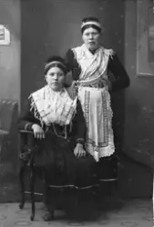 Studioportrett av to unge kvinner i samisk drakt. Den ene si