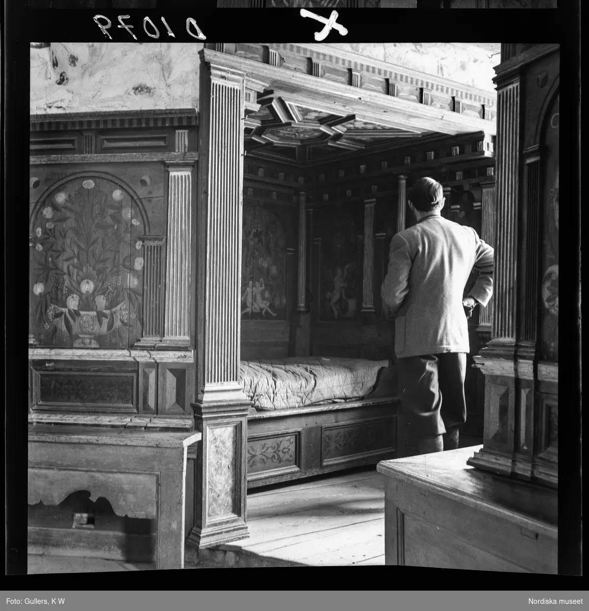 511 Gripsholms Slott för Allers. En man står framför en säng placerad i alkov i Hertig Karls kammare.