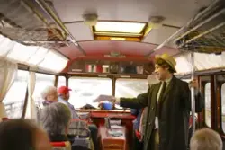 Innsiden av en veteranbuss hvor en visesanger underholder de reisende