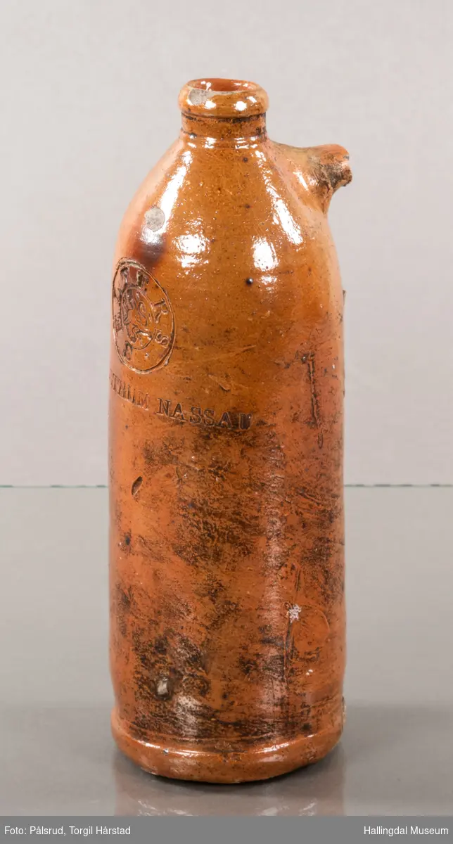 Keramikkflaske med ødelagt hank. Rustbrun, glassert.
