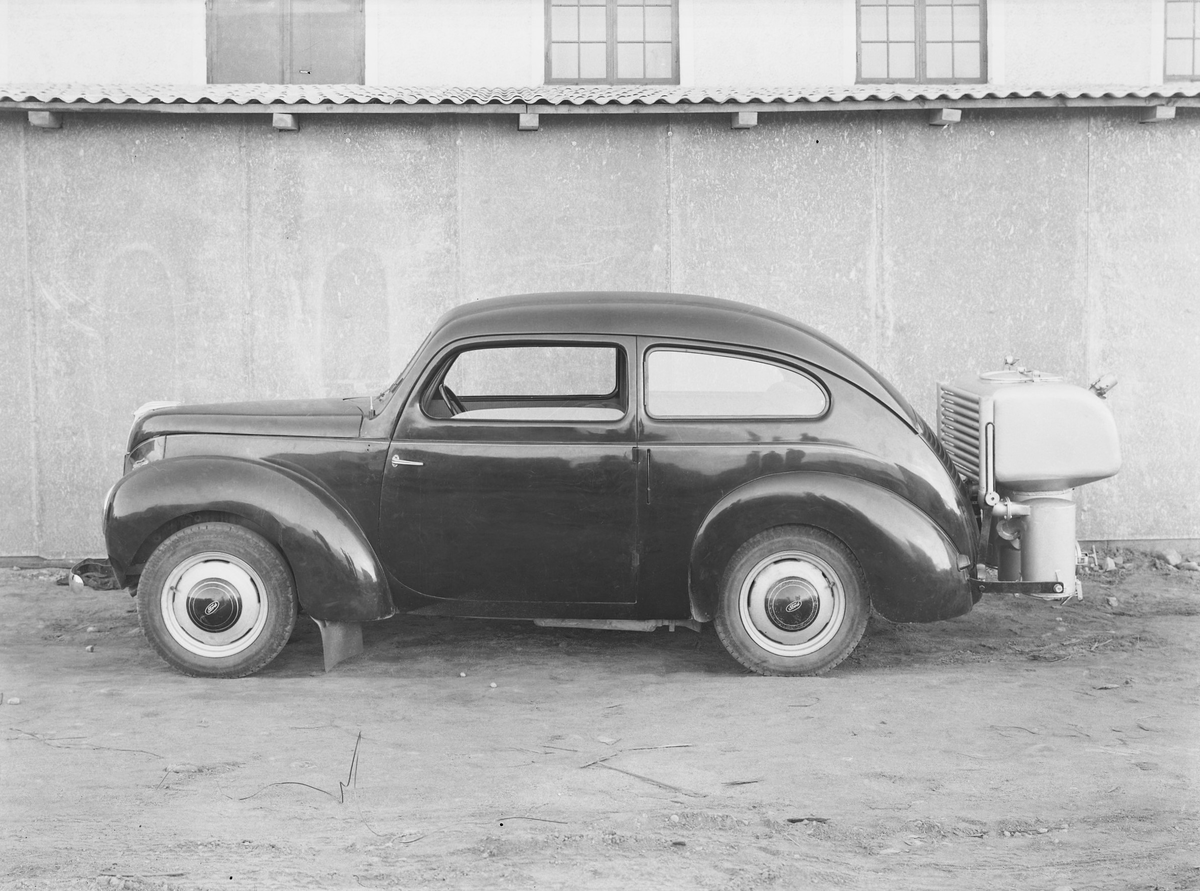 Personbil med gengasaggregat under andra världskriget. Eftersom importen av bensin och annat fordonsbränsle förhindrades under kriget användes i Sverige och Finland gengas som drivmedel. Bilden beställdes av Monark.