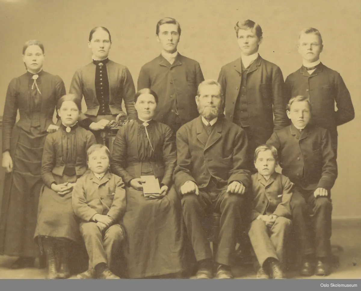Oppstilt foto av en familie på 11 personer. En av damene skal være lærerinne Hulda Amalie Tande (født 03.07.1864).