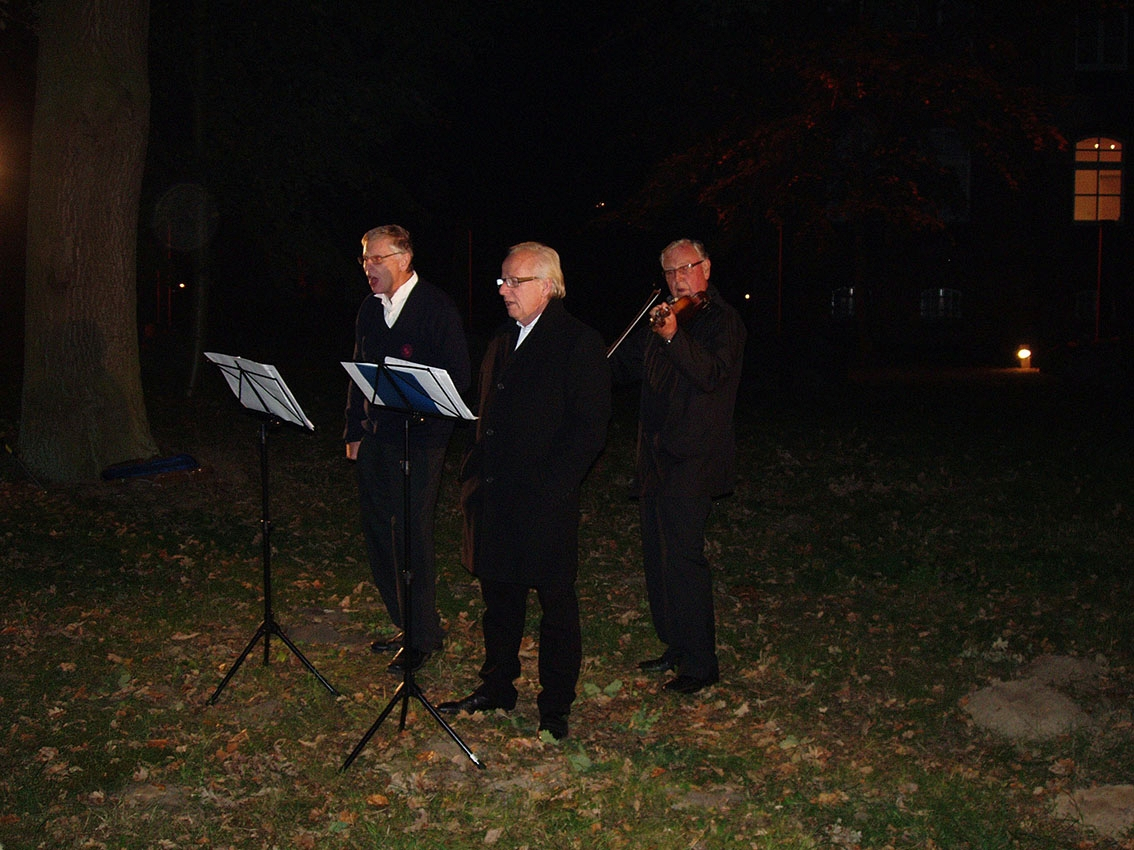Två sjungande män och en tredje som spelar fiol, en mörk septemberkväll.