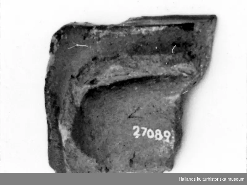 Arkeologiskt föremål. Fragment. Rödbränd lera. Svart glasyr. Hörnbit, förmodligen till friskakel. 
1600-tal