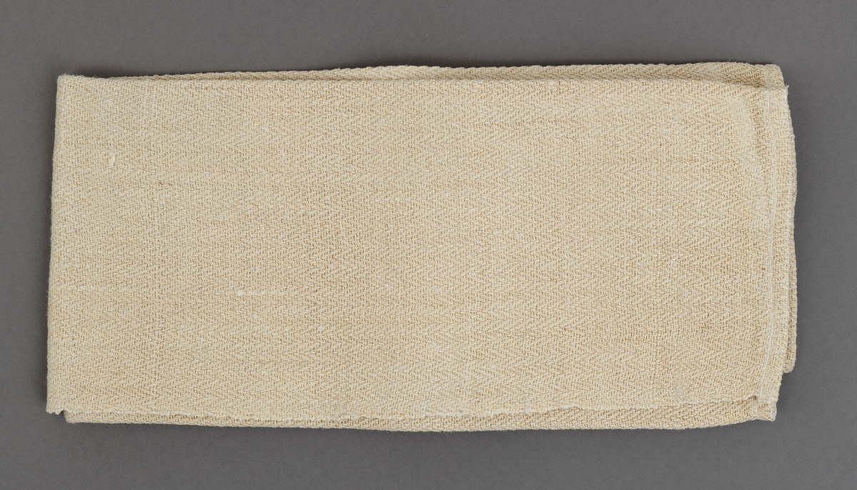 Noenlunde rektangulært kjøkkenhåndkle, antakelig vevd av lin med en antydning til lys, grågul fargetone. Stoffet er cirka 48 centimeter bredt, og lengden er 70 centimeter. Håndkledet er kantet i tverrendene, og på baksida, i begge ender er det påsydd 10,5 og 11 centimeter lange og 1,3 centimeter brede bedelbånd for oppheng. Denne tekstilgjenstanden ble avlevert til museet i pent strøket tilstand, brettet to ganger i bredderetningen og en gang i lengderetningen. 

Det fortelles i familien Karlsen at Inga kjøpte sammetraset garn fra Oslo seilduksfabrikk billig, og fikk ungene til å hjelpe seg å greie ut og nøste det. Dette garnet brukte hun i vevnader og andre tekstilprodukter.