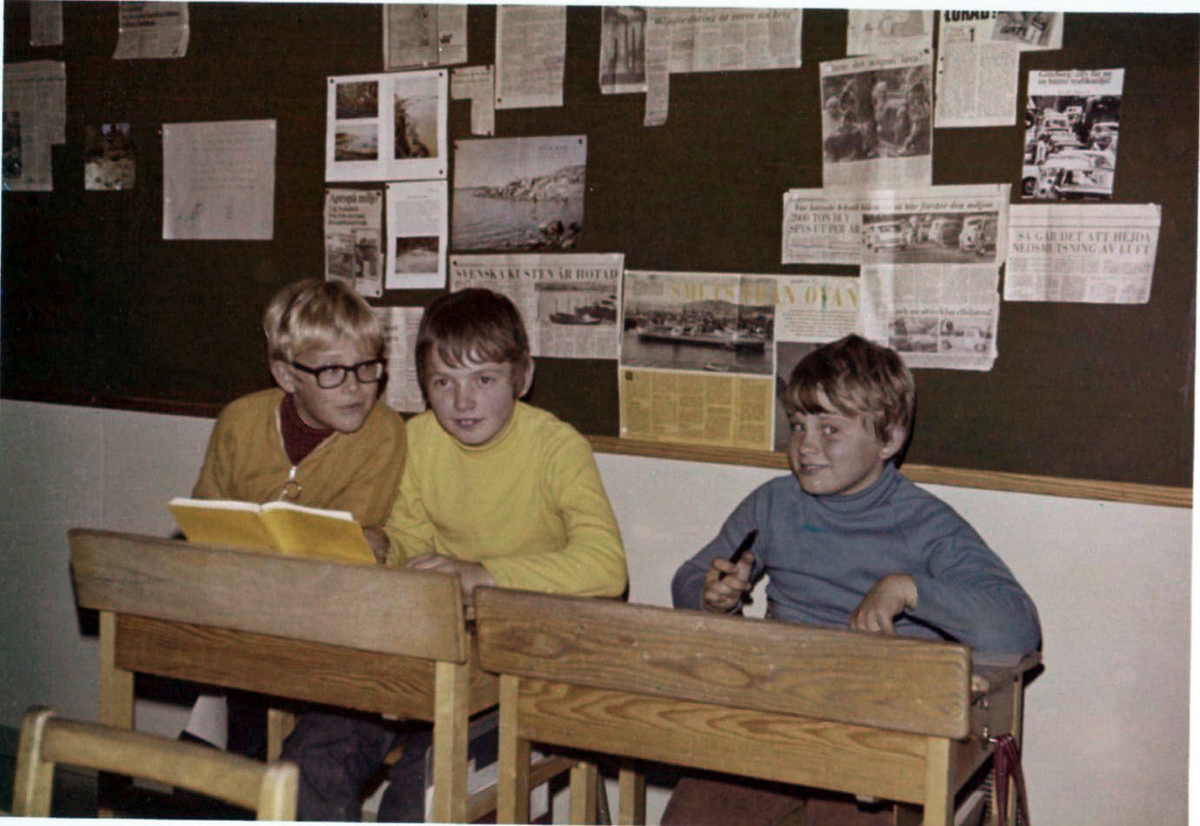 Tre elever (pojkar) sitter vid sina bänkar i en skolsal på Brattåsskolan, 1980-tal.