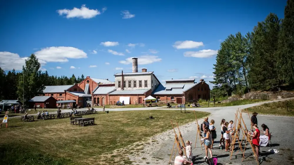 Klevfos industrifabrikk i solskinn. Mange barn leker foran