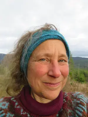 Kvinne med lilla ullgenser og blått pannebånd 