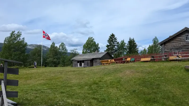 Panoramabilde av Målstua og Buflodsstua. En sommerdag med det norske flagget i falggstanga. 