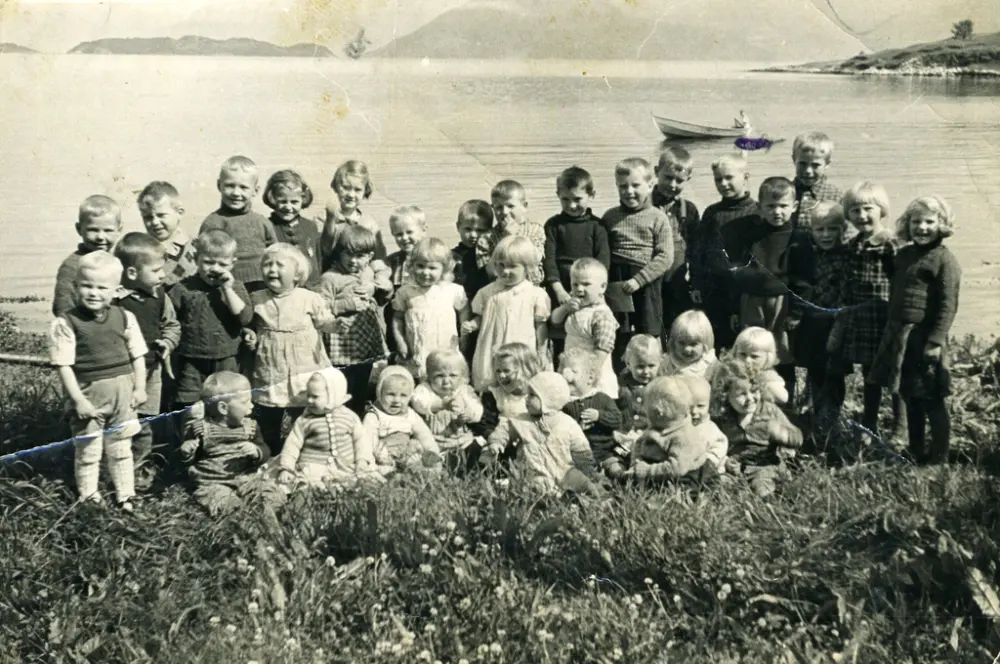 Ein stor flokk med born frå Telavåg ved ei strand på Framnes i Hardanger.