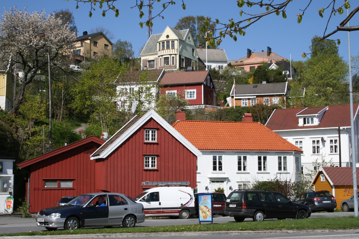 Bebyggelse i strandstedet Barbu. Kjøpmannsgård og gammel sjøbod. Sjøen sto inn til det røde huset sentralt i bildet. I bakgrunnen bebyggelse ved Skydebaneveien, bl.a. Barbu skole.