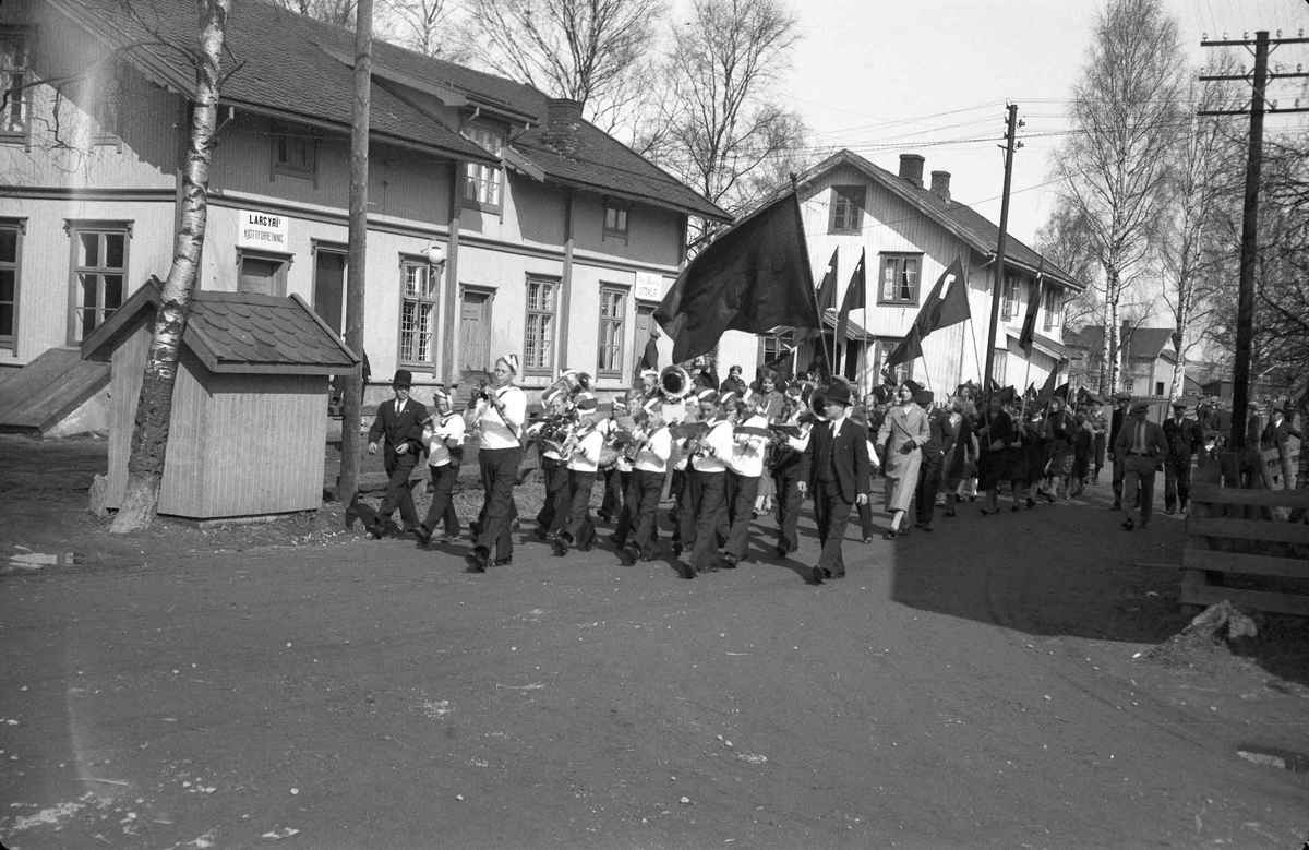 Korps marsjerer foran 1. maitog på Bøn foran LARS YRI kjøttforretning. Bilde fra før krigen. 