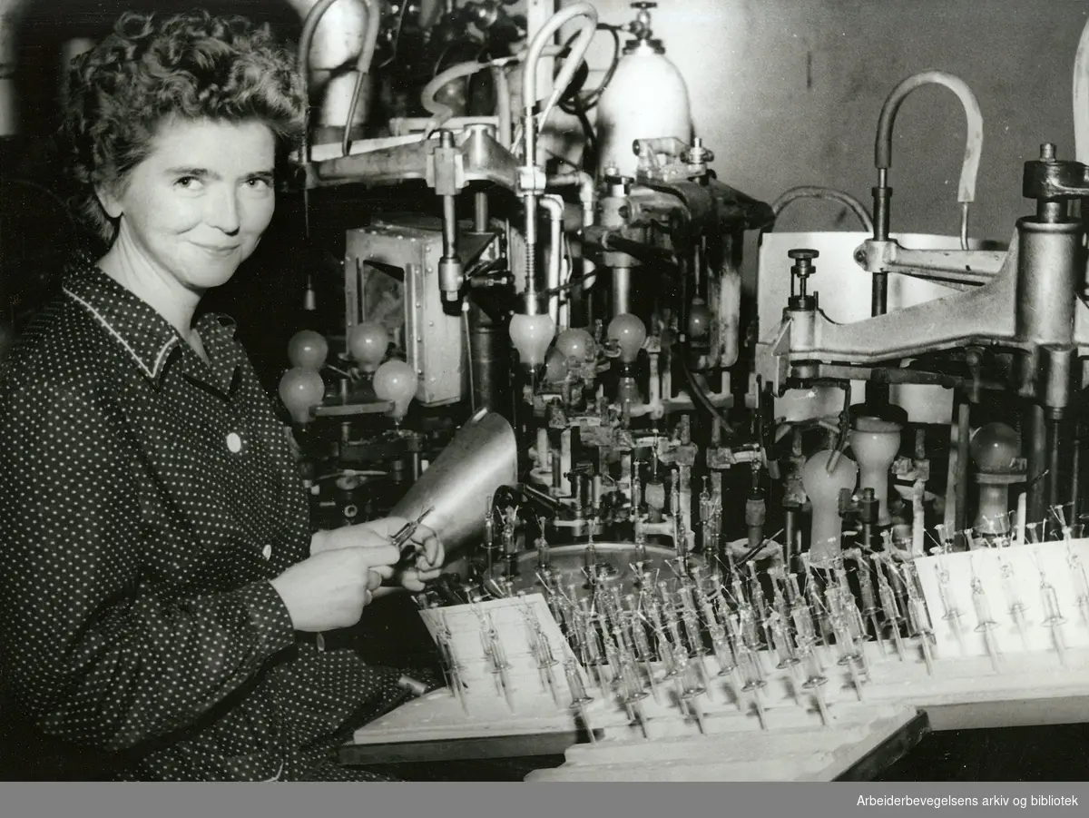 Lyspæreproduksjon ved Luma fabrikker,.Lissy Fredriksen ved innsmeltningsmaskinen,.ca. 1960