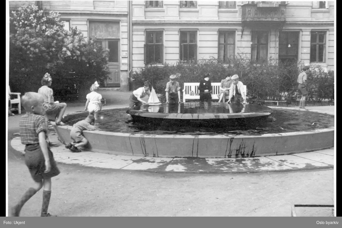 Barn i lek ved fontenen i Stensparken. Husfasade i Stensgata 22 i bakgrunnen.