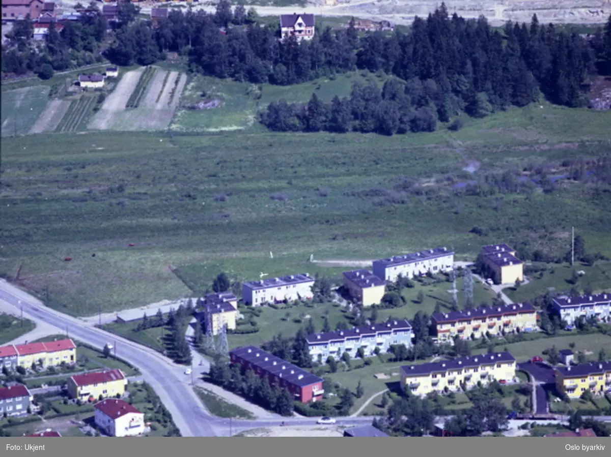 Østensjøveien til venstre, rekkehusene i Langerudhaugen og Langerudsvingen mot høyre. Bogerudmyra i bakgrunnen. (Flyfoto)