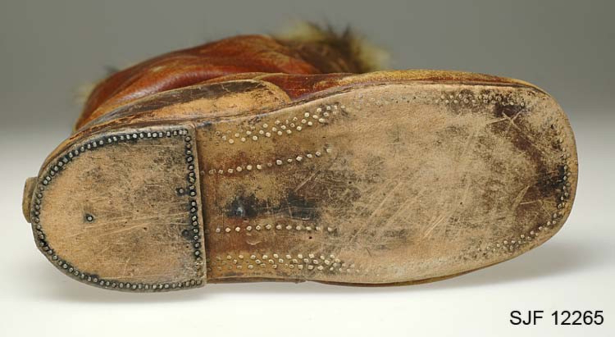 Høyskaftede lærstøvler med plugget såle, foret med saueskinn og kantet med ilderskinn? Beskyttelsesknapp plugget bak på hælen, anvendelig når skoen skal tas av.