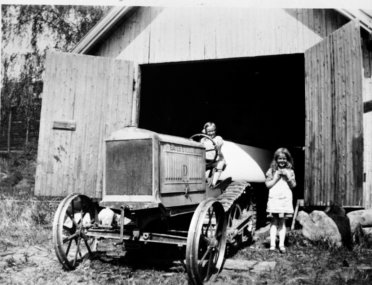 Den første traktoren på Hovelsrud, Helgøya. 2 småjenter. Kirsten Augusta Louise (Lillemor) f. 1923 og Valborg Leonore (Vesla) f. 1922. Denne traktoren er en half-track Bates Steel Mule modell D 15-22. 4 cyl. petrol/paraffin, bygget i 1919/20 i Joliet, Illinois.