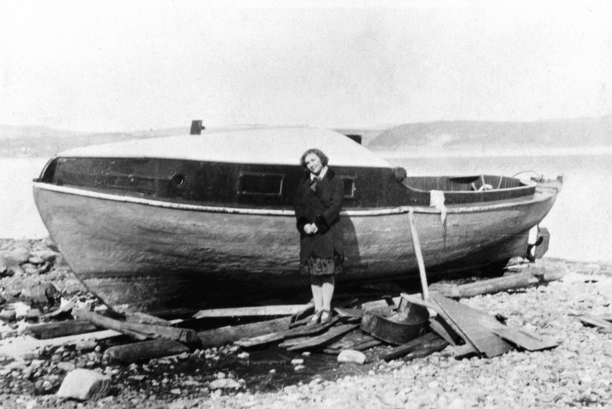 Dame ved motorbåt på Mjøsstranda, Grefsheim, Nes, Hedmark. Båten er M.B Karine som tilhørte Grefsheim.