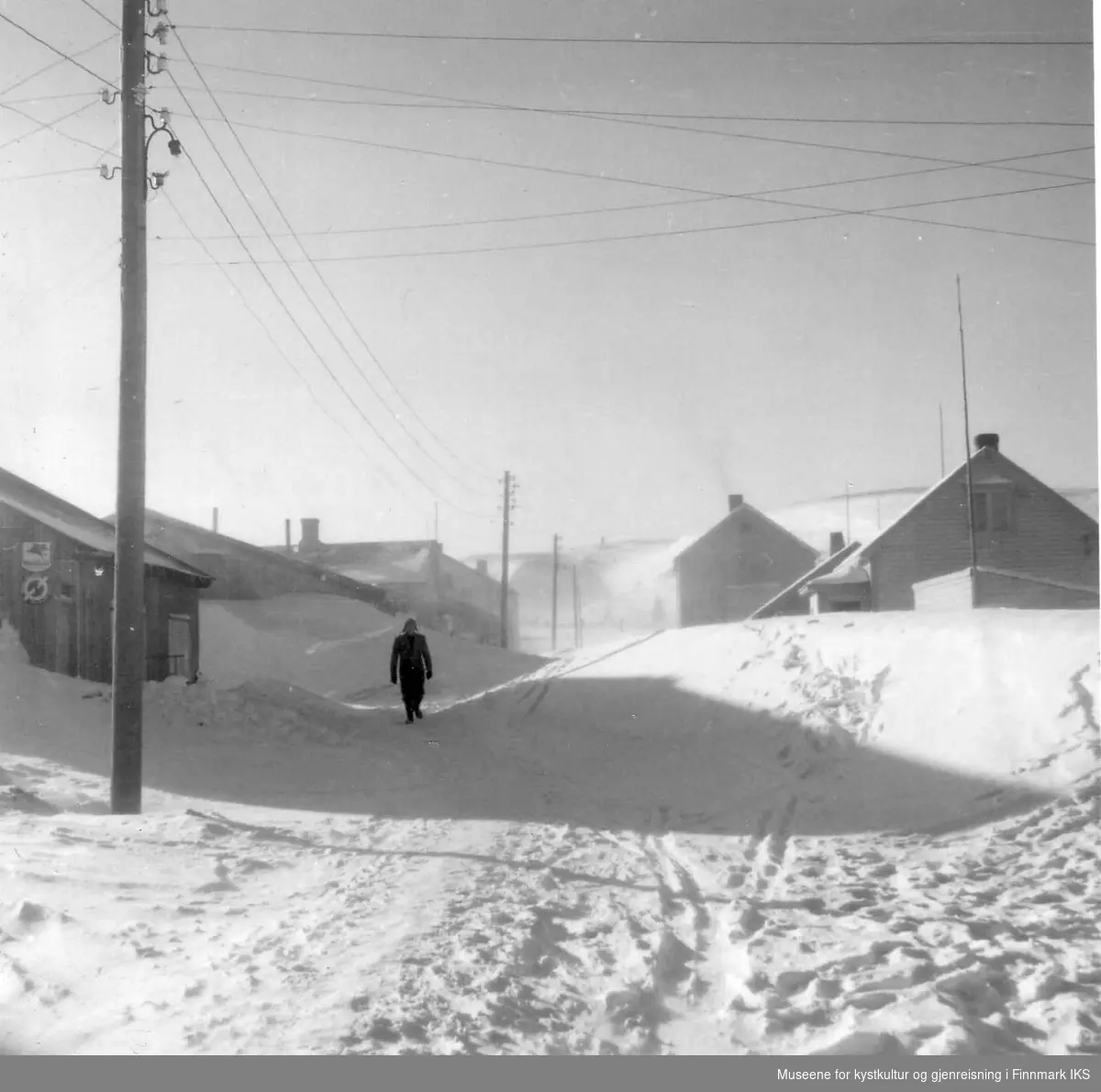 Snøforholdene i J.M.Withsgt. Fotoet er tatt fra Storgt og oppover. Til venstre Svein Johansens brakke-butikk. Det store huset øverst til høyre er Sandmohuset. 1952
