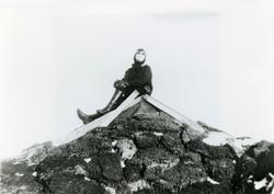 Ingunn Sandtröen sitter på et gammetak i sola., ca 1955