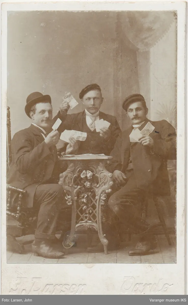 Gruppeportrett, tre menn poserer med kort og pengesedler