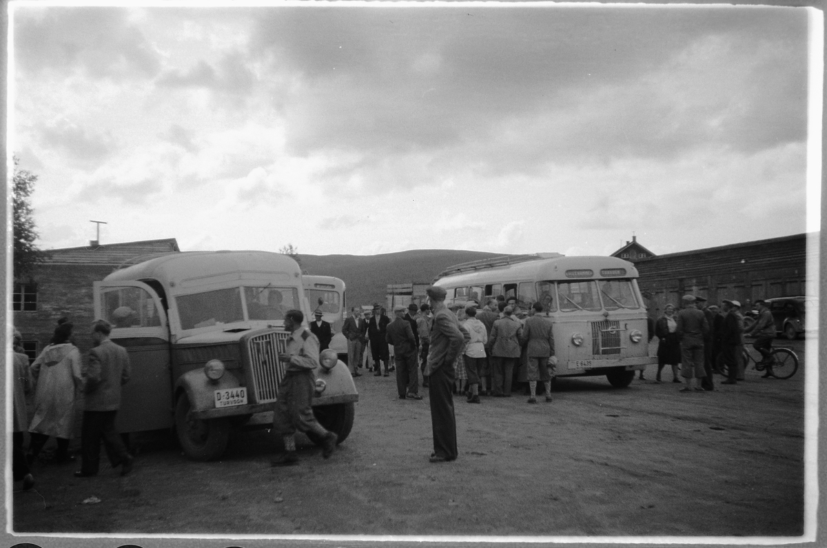 Gruppe mennesker stiger ombord på to busser. Busstur, buss, rutebil. Kjøretøy til venstre i bildet med reg. nr. D-3440 er en Opel blitz, førkrigsmodell, eier er A/S Nygard Landhandel, Lismarka. Kjøretøy til høyre i bildet har registreringsnummmer E-6435.D-3440 Opel Blitz 1938-mod. var tysk etterlatenskap som Nygård Landhandleri fikk kjøpt i 1946. Bussen gikk inn i Lillehammer-Ringsaker Bilruter (LRB) ved sammen-slutningen i 1951. E-6435 Volvo 1950-mod.: Bussen ble opprinnelig registrert som E-6390 på Iversens Bilcentral A/S, men skiftet til nytt reg.nr. da Iversens gikk inn i LRB i 1951.
