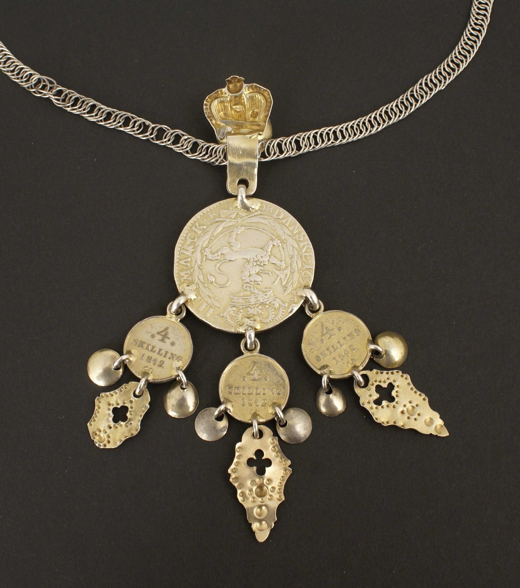 Smykket har langt håndlaget panserkjede i sølv, også kalt flatlenke, og hempe for anheng med krone og lauv.