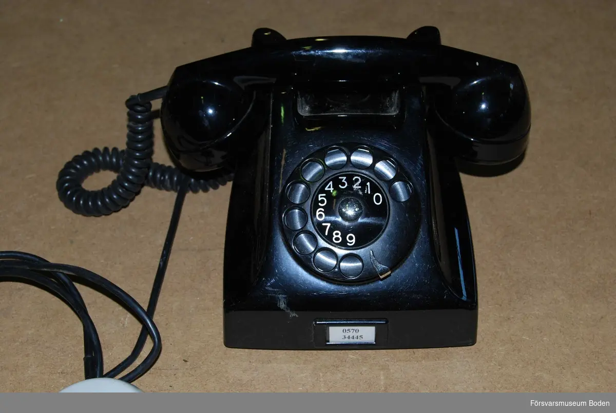 Äldre telefon av svart bakelit, troligen tillverkad vecka 51 1963 med ledning av märkningen på undersidan.