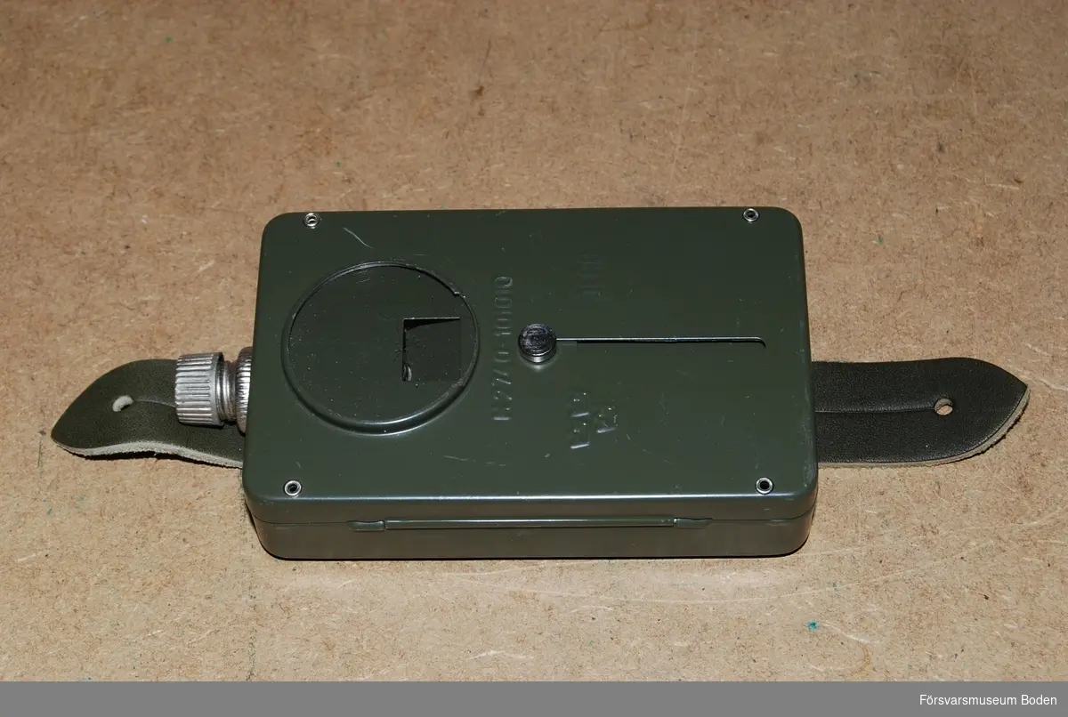 Av grönlackerad plåt, avsedd för 4,5 volts batteri. Avskärmning i form av skjutbart lock.  Av- och påslag genom vridreglage upptill. Framsidan präglad med tre kronor och materielnummer M2740-101010.