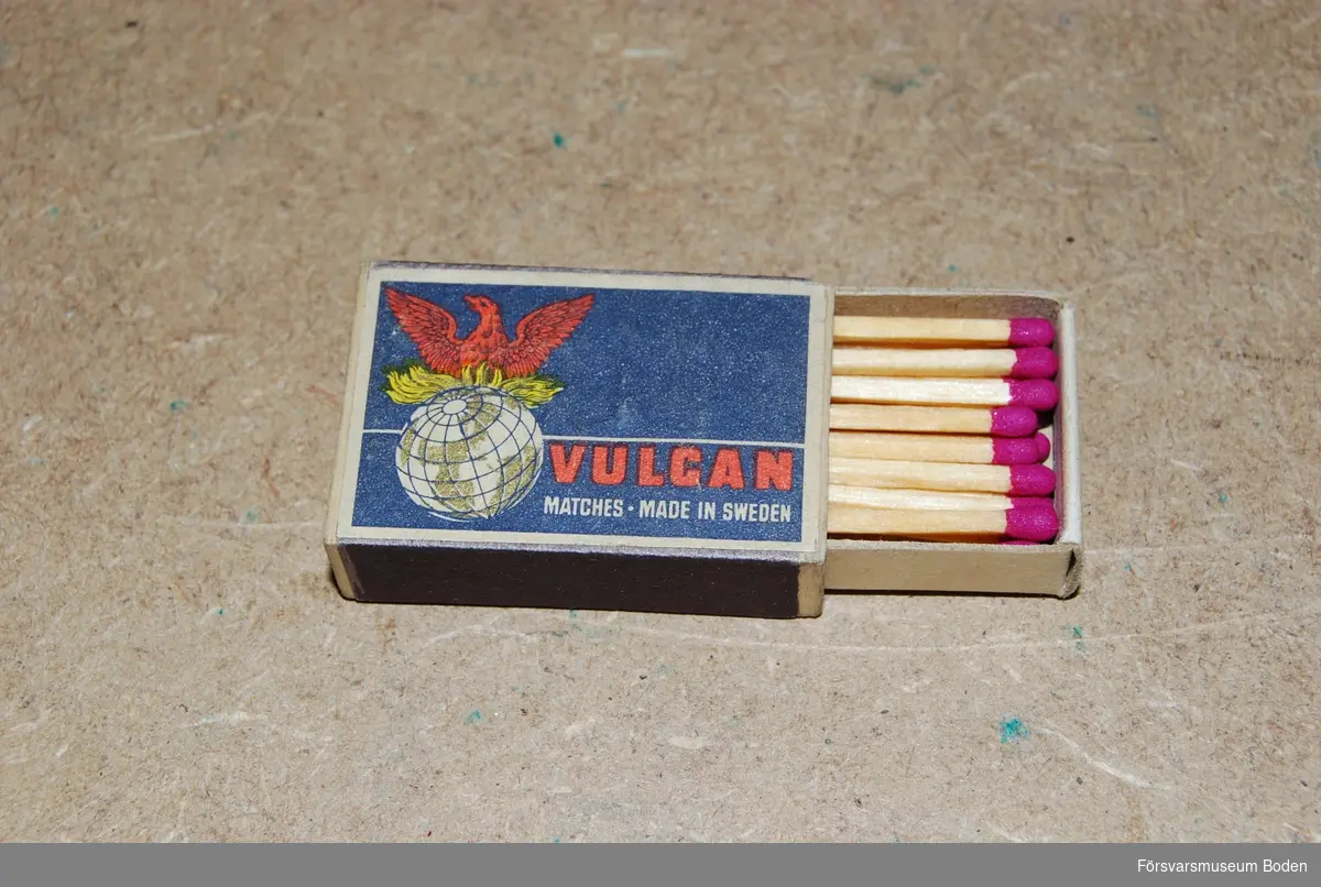 Liten ask 42 x 28 x 12 mm med blå och röd etikett för varumärket Vulcan. Tändstickorna har rött svavel.