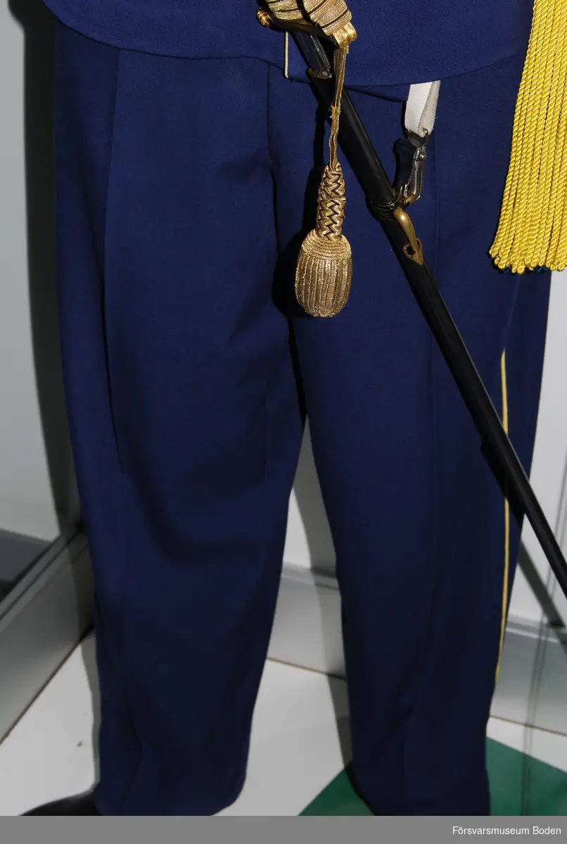 Mörkblått kläde med gula passpoaler längs yttersömmarna. Knappar på byxbenens insida nertill vid anklarna.