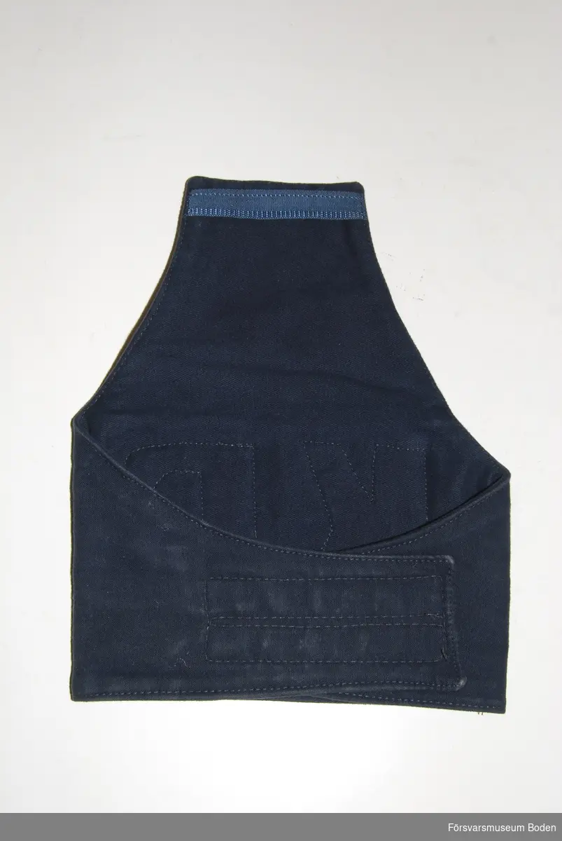Bindel av mörkblått tyg, troligen handsydd och försedd med bokstäverna "KP" i grå vinylplast. Kardborrelåsning på baksidan.