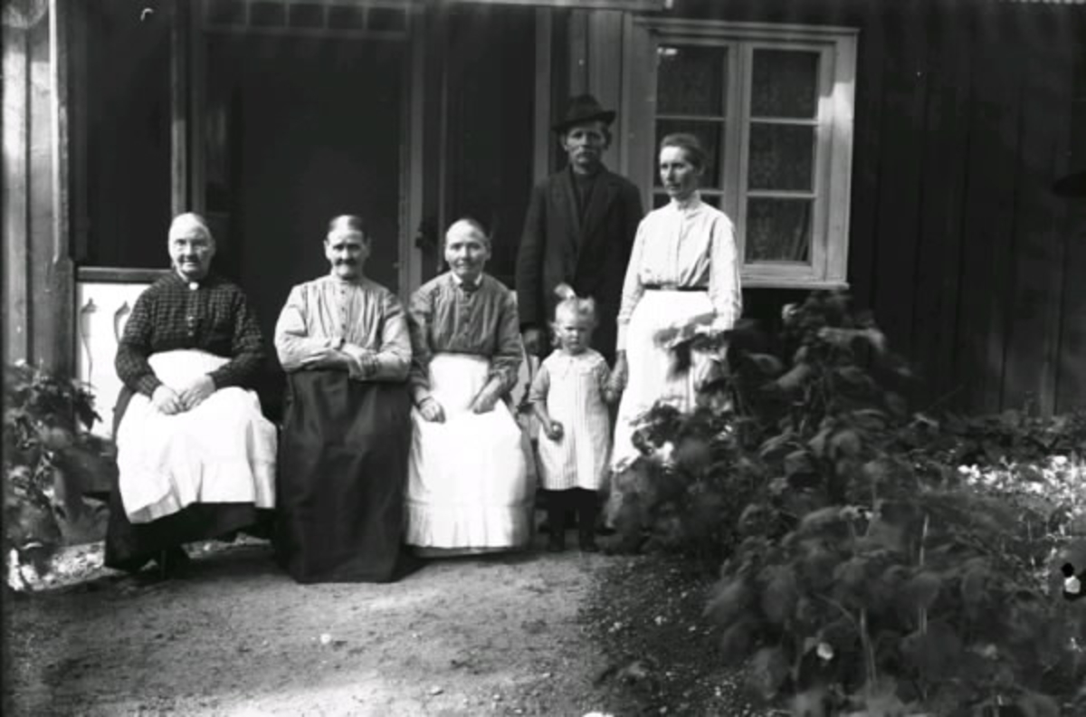 Fyra kvinnor, ett flickebarn och en man vid farstukvisten till ett hus i Drängsereds socken.