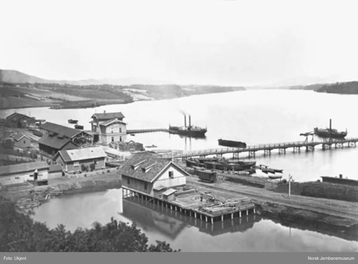 Oversiktsbilde med Eidsvoll stasjon, to dampbåter, beddingen med to klinkbygde lektere og brua over Vorma