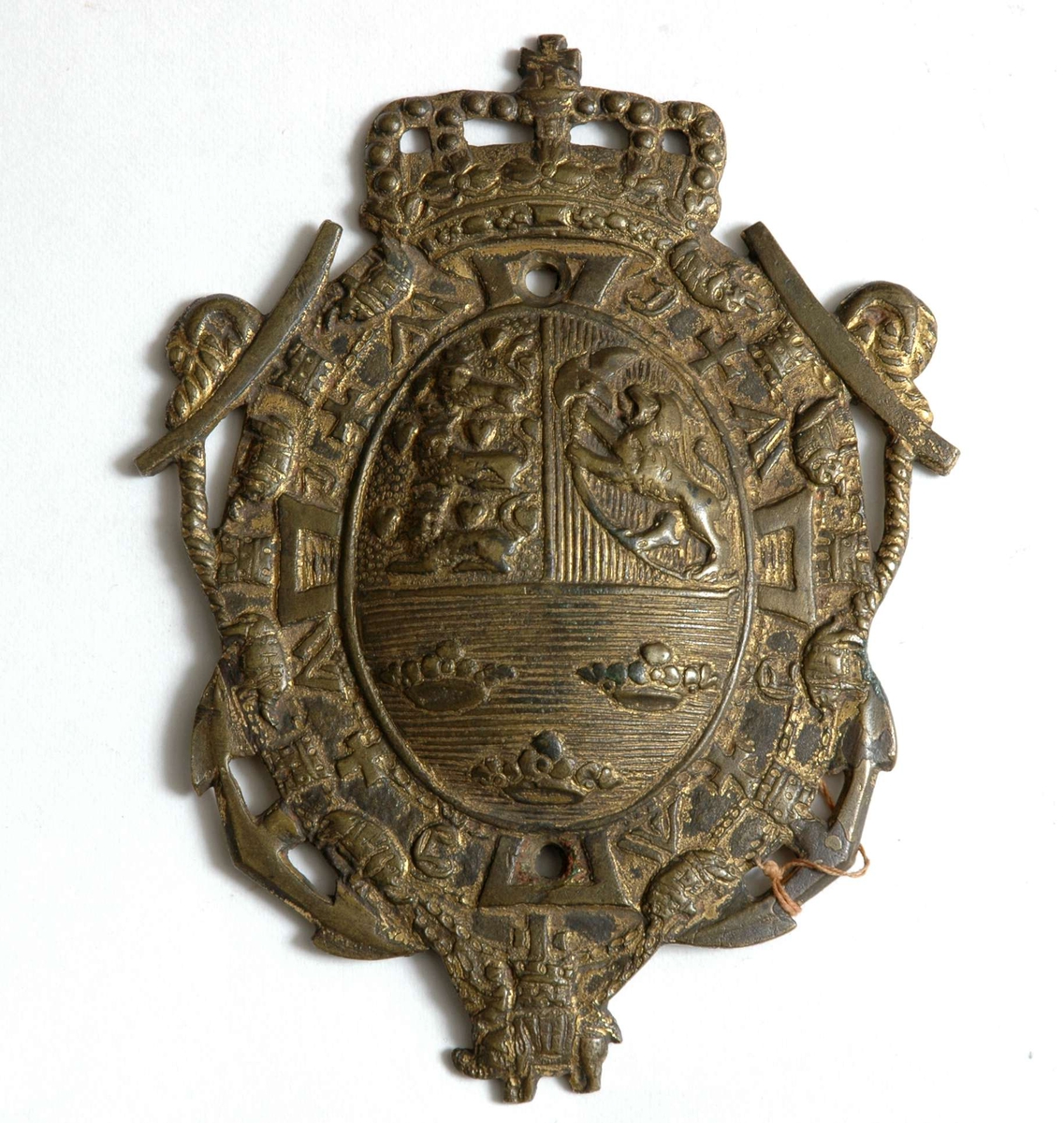 Ovalt messingskilt med det kronede tredelte dansk-norske riksvåpenet med Elefantordenen i bunn
Skiltet har rester av forgylling.