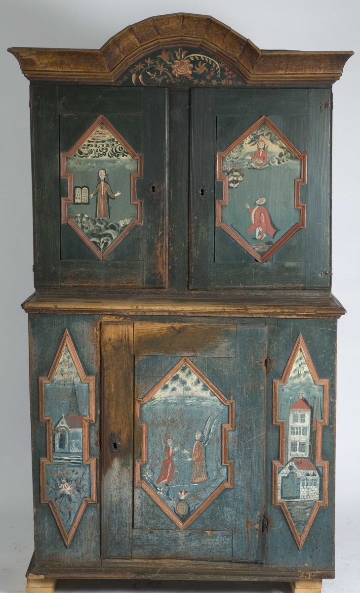 Skap, framskap i en del, to dører oppe og nede. Bibelske motiver; Moses og de ti bud. Gud på en sky, en brennede sky eller busk, en mann som har mistet en sko og en stokk.