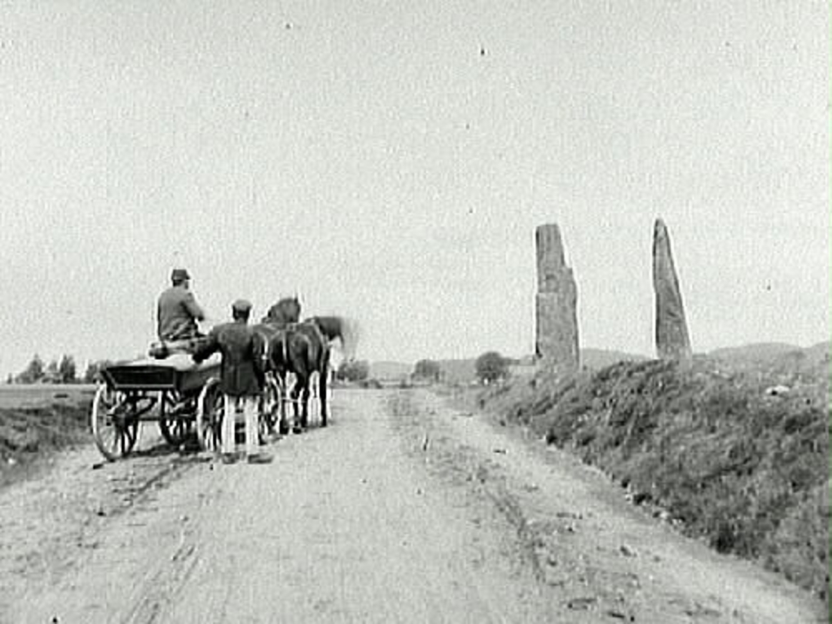 Hagbards galge och Signes galge vid Asige hed. På vägen står ett hästekipage med två män som betraktar stenarna.