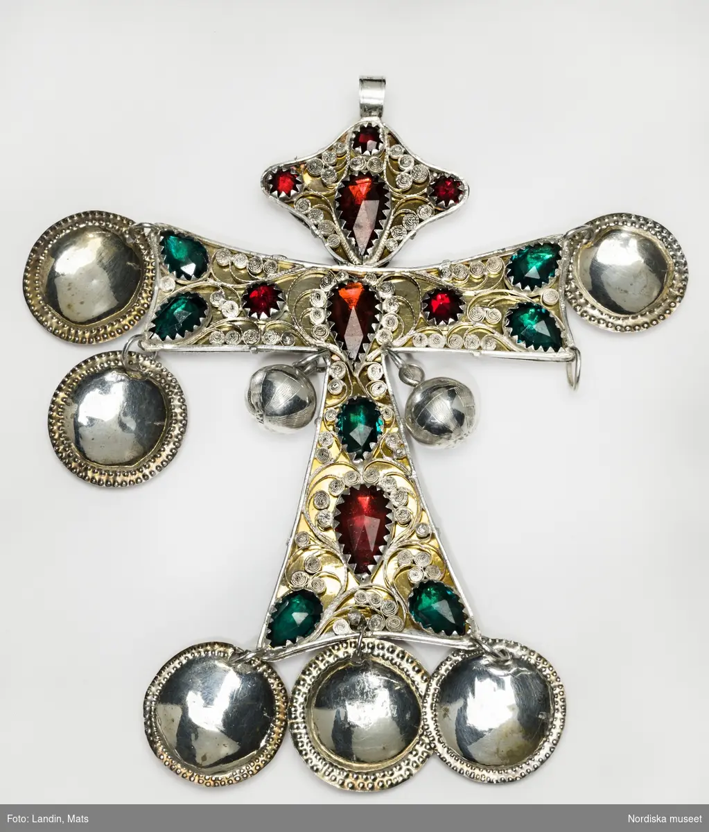 Huvudliggaren:
"Striglakors fr. Skåne.
Af silfver, med inlagda stenar; stort, utmärkt vackert.
G. af guldsmeden G. Dahlberg i Lund 13/2 1877."

Striglakors av silver med filigrandekor och 15 stycken infattade glasstenar i rött och grönt, mot förgylld bakgrund. Krönets kontur i form av stiliserad ängel. Från korsarmarna sex stycken förgyllda skålformade hängen, ett saknas, samt två graverade silverkulor stämplade AH. På smyckets baksida finns två stämplar. Den ena stämpeln är förmodligen mästarstämpell ÅÅ, Åke Åkesson, Simrishamn (verksam 1826-1866), den andra stämpeln kan vara Simrishamns stadsstämpel.  
/Conni Hultberg/Marie Tornehave 2008

Vid utställning 2012 kompletterades striglakorset med ett skålformat hänge (äldre) på den högra korsarmen (sedd framifrån), nedtill. Utfört av konservator Kerstin Jonsson.
/Leif Wallin 2012-05-28