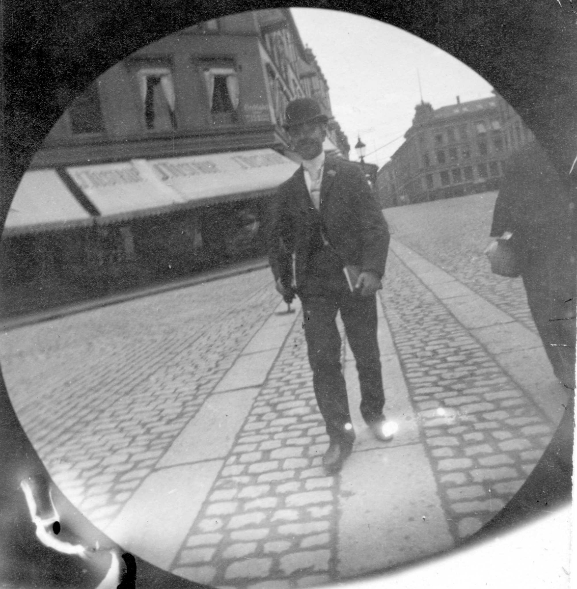 Herman Reimers spaserer langs Karl Johan, Oslo, ved Tostrupgården med bok under armen.