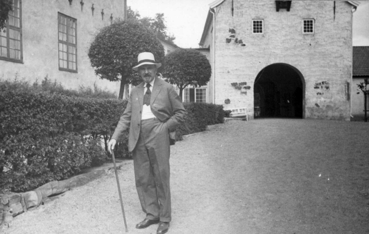 Direktør Hans Aall i Friluftsmuseet i 1934, ikledd hvit hatt og med stokk.
Bergensporten, bygning nr. 301, i bakgrunnen.
