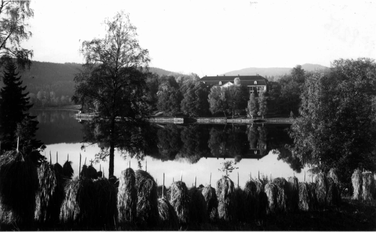 Bogstad gård og Bogstadvannet ca. 1923. Hovedbygningen i bakgrunnen. Kornstaur i forgrunnen.